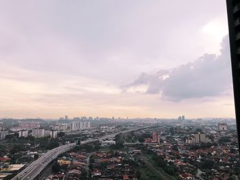 Aerial view of cityscape against cloudy sky