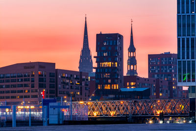 Illuminated buildings in city during sunset