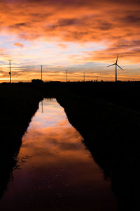 Silhouette of traditional windmill against sky during sunset