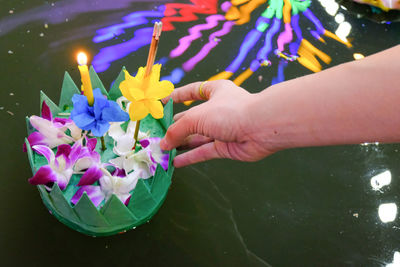 Cropped hand of woman holding religious offering over pond