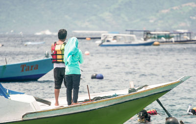 Rear view of man and woman standing on boat at sea