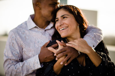 Multiracial late forties couple embracing at sunset in san diego