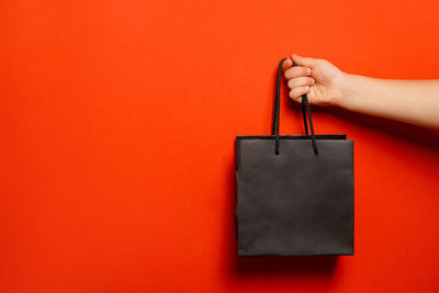 Cropped hand of woman holding gift against yellow background