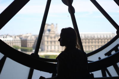 Rear view of silhouette woman looking through window