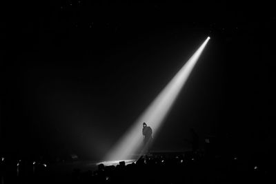 Silhouette singer singing while standing on stage at night