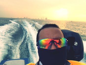 Close-up of man in sea against sky during sunset