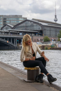 Rear view of woman sitting on bollard