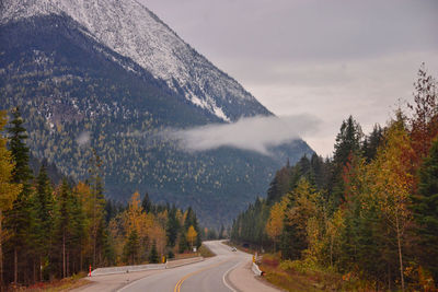 Road amidst trees against sky during autumn