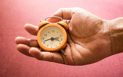 Close-up of hand holding alarm clock above seat