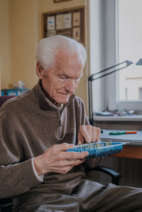 Smiling man holding seedlings in tray at home