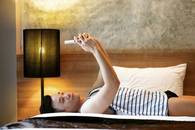 Man taking selfie while lying on bed