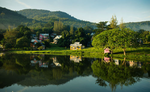 Houses and tree mountain reflecting on calm lake