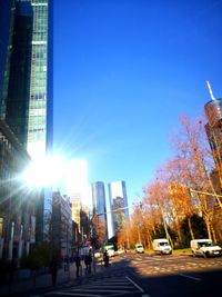 City street by buildings against clear sky on sunny day