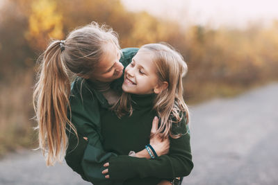 Portrait of happy mature mom and her blonde little daughter hugging and laughing