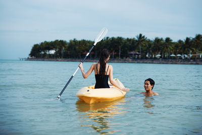 Man kayaking in sea against sky