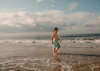 Full length of boy on beach against sky