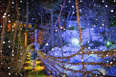 Woman standing on footbridge during snowfall at night