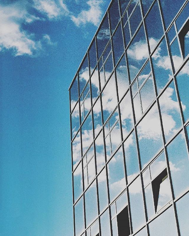 low angle view, architecture, modern, building exterior, built structure, office building, glass - material, reflection, blue, sky, skyscraper, city, building, tall - high, tower, day, pattern, window, glass, cloud - sky