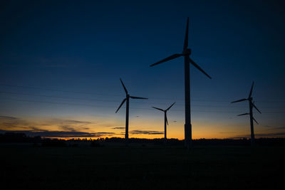 Power generators of windmills at shadow sunset - wind turbine on field at sunset