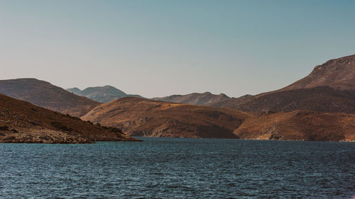 Scenic view of sea and mountains against clear sky