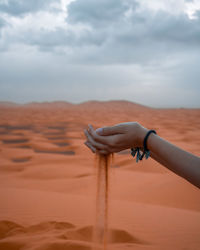 Cropped hand of man holding sand at beach