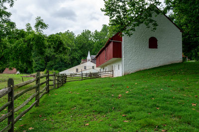 Houses by trees on field against sky