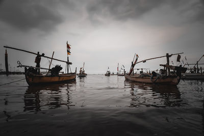 Fishing boats in sea against sky