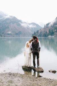 A loving married couple the bride and groom in suits celebrate wedding near the mountains and water