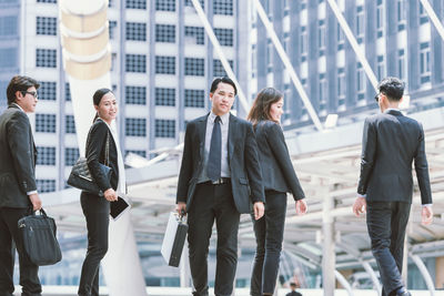 Businesspeople standing on steps by buildings in city