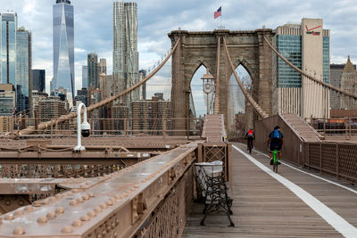 Suspension bridge in city against sky