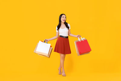 Portrait of a smiling young woman against yellow background