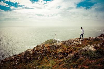Man standing on mountain by sea against sky