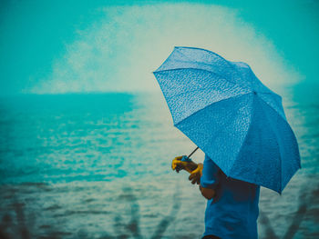 Man holding umbrella on beach