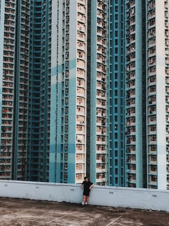 FULL LENGTH OF MAN STANDING AGAINST OFFICE BUILDINGS