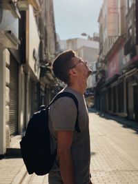 Side view of young man standing in city