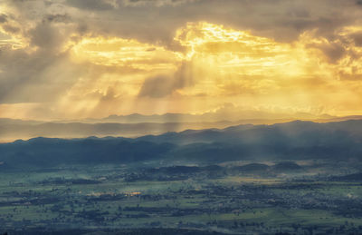 Scenic view of landscape against dramatic sky during sunset