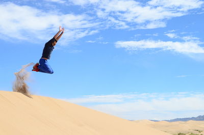 Low angle view of man jumping against sky 