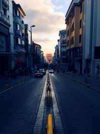 Street amidst buildings in city against sky during sunset