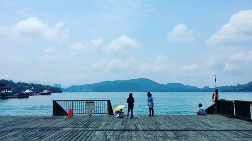 Rear view of people overlooking calm lake