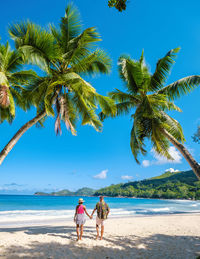 Rear view of woman walking at beach against sky