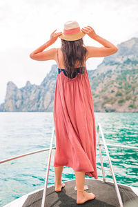Rear view of woman standing by boat in sea