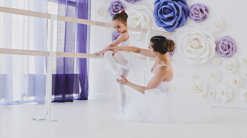 Dancer teaching girl in ballet studio