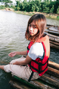 Portrait of woman sitting on wooden raft in lake