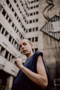 Portrait of young man standing against building in city