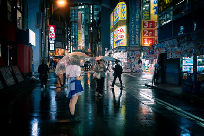 People walking on wet road in city during rainy season