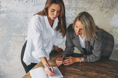 Coworkers discussing against wall in office