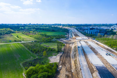 Aerial top down view of an unfinished asphalt covered road heavy machinery at construction site.