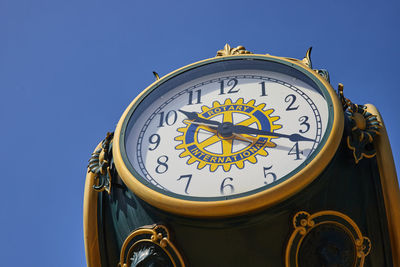 Close-up of clock against blue sky