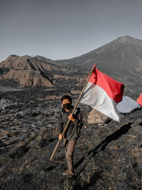 Midsection of man holding umbrella against mountain range