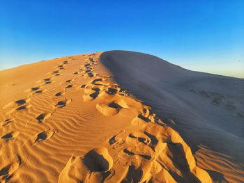 Scenic view of desert against clear blue sky